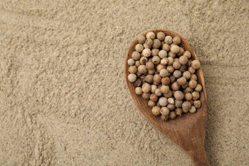 Aromatic spice. Spoon with peppercorns on ground black pepper, top view