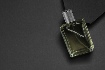 Stylish presentation of luxury men`s perfume in bottle on black background, top view. Space for text