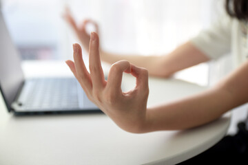 Close up image of woman's hands who was sitting and meditating at his desk in a white office To...