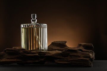 Luxury men`s perfume in bottle on table against brown background, space for text