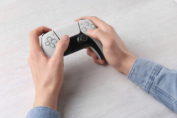 Man using wireless game controller at white table, closeup