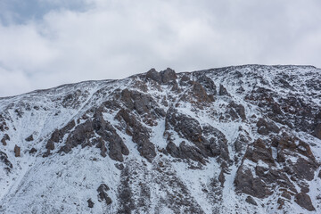 Snow-white landscape with large snow-covered mountain range with sharp crags on top. Dramatic...