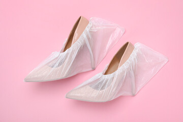 High heels in shoe covers on pink background, top view