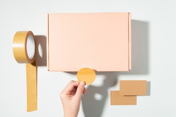 Mailing box, hand attaching sticker, flat lay design