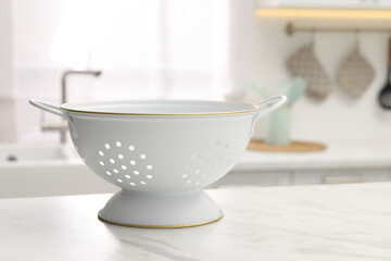 Clean colander on white marble table in kitchen. Space for text