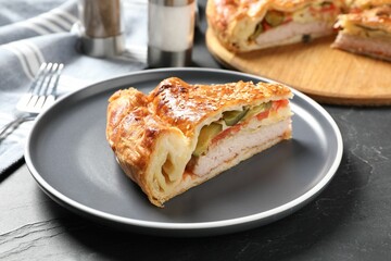 Piece of tasty homemade pie with filling on dark grey table