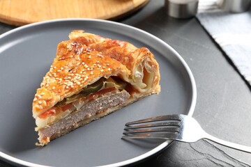 Piece of tasty homemade pie with filling on dark grey table