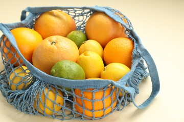 String bag with different fruits on beige background, closeup