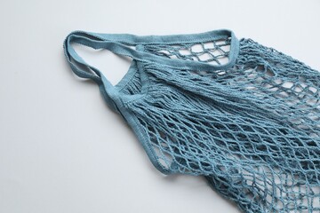 Blue string bag on light grey background, top view
