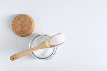 Baking soda in jar and spoon on white background, top view. Space for text