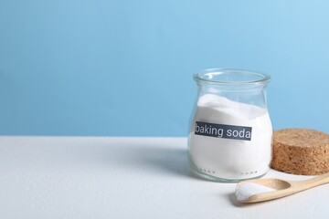 Baking soda in jar and spoon on white table. Space for text