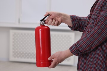 Man with one fire extinguisher indoors, closeup