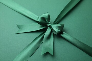 Bright satin ribbon with bow on green background