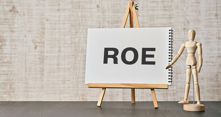 There is notebook with the word ROE. It is an abbreviation for Return On Equity as eye-catching...
