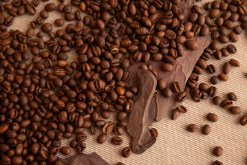 A pile of coffee beans on a table. The beans are scattered and some are piled