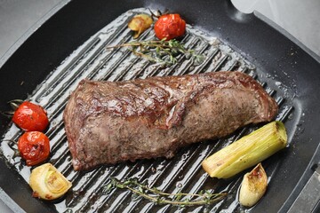 Delicious grilled beef meat and vegetables in pan on table, closeup
