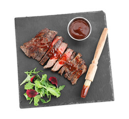 Pieces of delicious roasted beef meat with sauce and greens isolated on white, top view