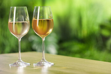 Tasty white wine in glasses on wooden table, space for text