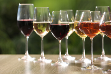 Different tasty wines in glasses on wooden table