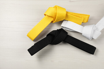Colorful karate belts on wooden background, flat lay