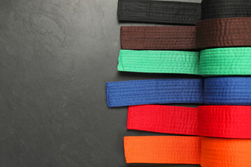 Colorful karate belts on gray background, flat lay. Space for text