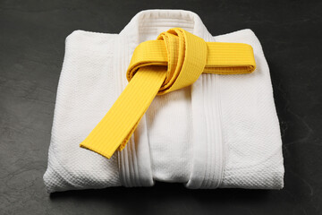 Yellow karate belt and white kimono on gray background