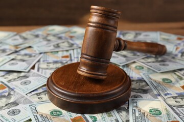 Judge's gavel and money on wooden table, closeup