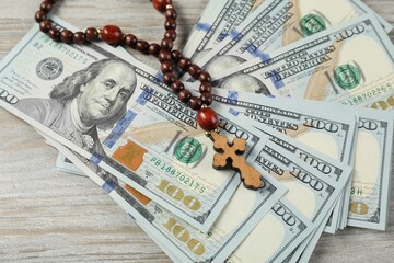 Cross and money on wooden table, closeup