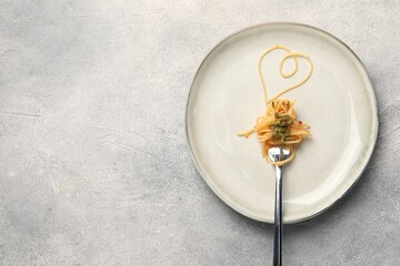 Heart made with spaghetti and fork on grey table, top view. Space for text
