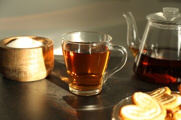 Tasty tea and sugar on dark table, closeup