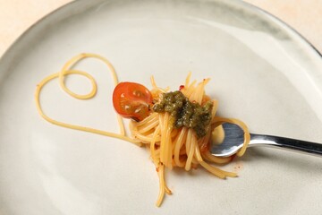 Heart made with spaghetti and fork on plate, closeup