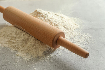 Flour and rolling pin on grey table, closeup