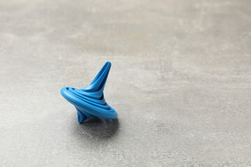 Blue spinning top on grey textured background, closeup. Space for text