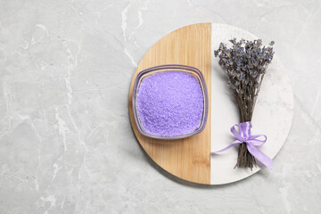 Violet sea salt in bowl and lavender flowers on grey marble table, top view. Space for text