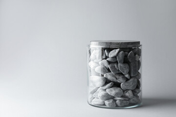 Presentation for product. Glass container with stones on light grey background. Space for text