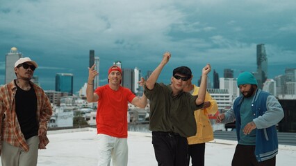 Skilled multicultural street dancing group pose at camera at roof top while moving to the rhyme and...