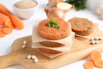 Uncooked carrot cutlets and ingredients on white wooden table. Vegetarian product