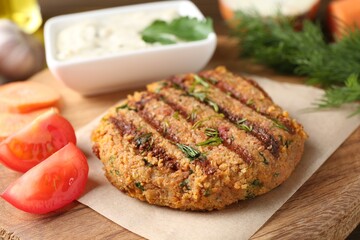 Delicious vegetarian cutlet served with tomato and sauce on wooden board, closeup