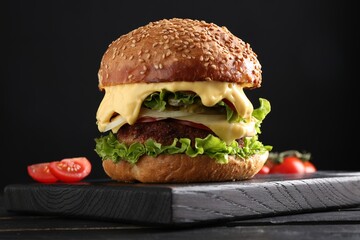 Vegetarian burger with delicious patty on black wooden table, closeup