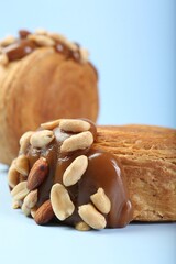 Supreme croissants with chocolate paste and nuts on light blue background, closeup. Tasty puff pastry