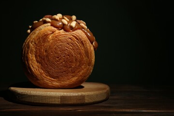 Round croissant with chocolate paste and nuts on wooden table, space for text. Tasty puff pastry