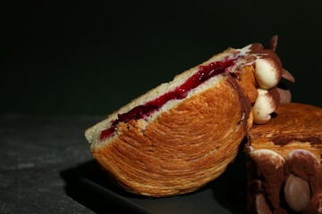 Tasty puff pastry. Round croissant with jam, cream and chocolate chips on grey table, closeup....