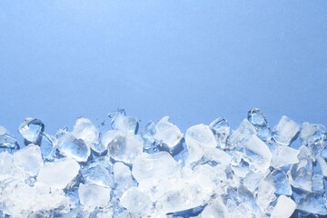 Pieces of crushed ice on light blue background, flat lay. Space for text