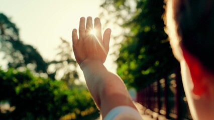 Children's prayer, boy stretches out his palm to sun. Happy child boy raises her hands to sun. Kid...