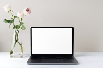 Aesthetic workspace with blank laptop screen and flower in vase