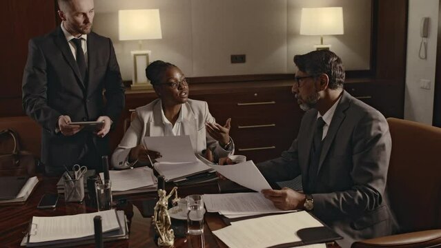 Side footage of diverse male and female lawyers consulting law firm manager on previous legal cases during conference in boardroom