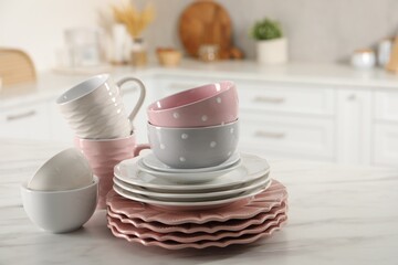 Many different clean dishware and cups on white marble table in kitchen