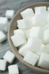 White sugar cubes in bowl on wooden table, closeup