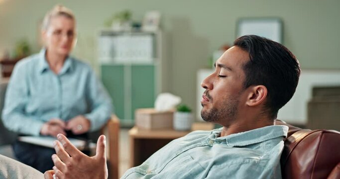 Therapy, talking and sad man with psychologist in office for mental health, anxiety or depression. Upset, stress and male person with emotions speak to medical worker for psychiatry advice in clinic.