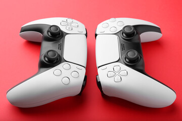 Two wireless game controllers on red background, closeup